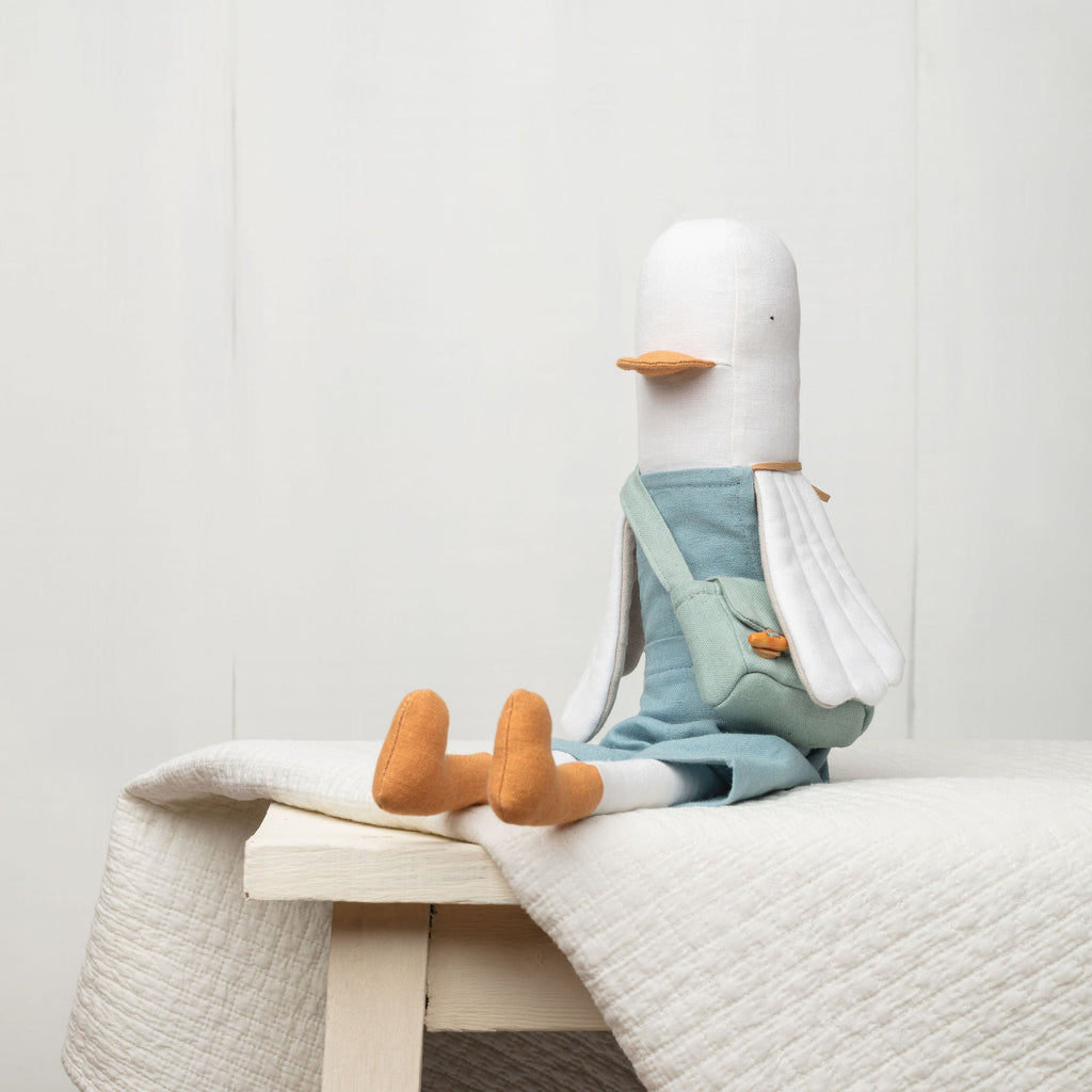 Plush duck toy with a blue diaper sitting on a white surface against a light gray background