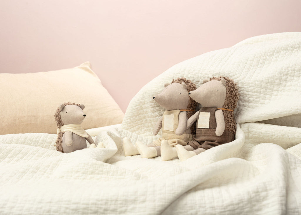 Three teddy bears sitting on a soft surface with a pink background