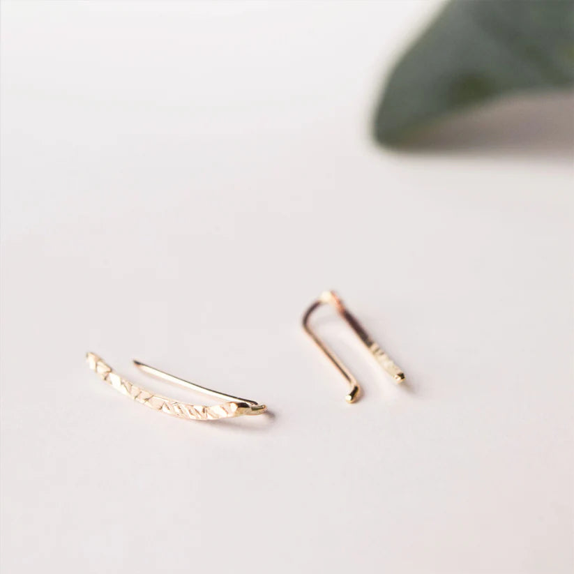 Pair of gold ear climbers; one features a textured, curved bar design.