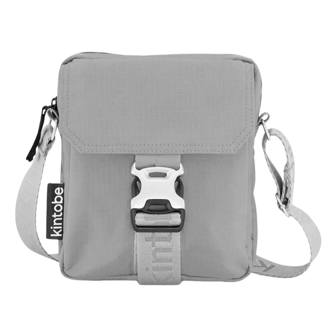 Gray crossbody bag with a silver and black buckle closure.  The bag features a small, rectangular shape and a branded label.