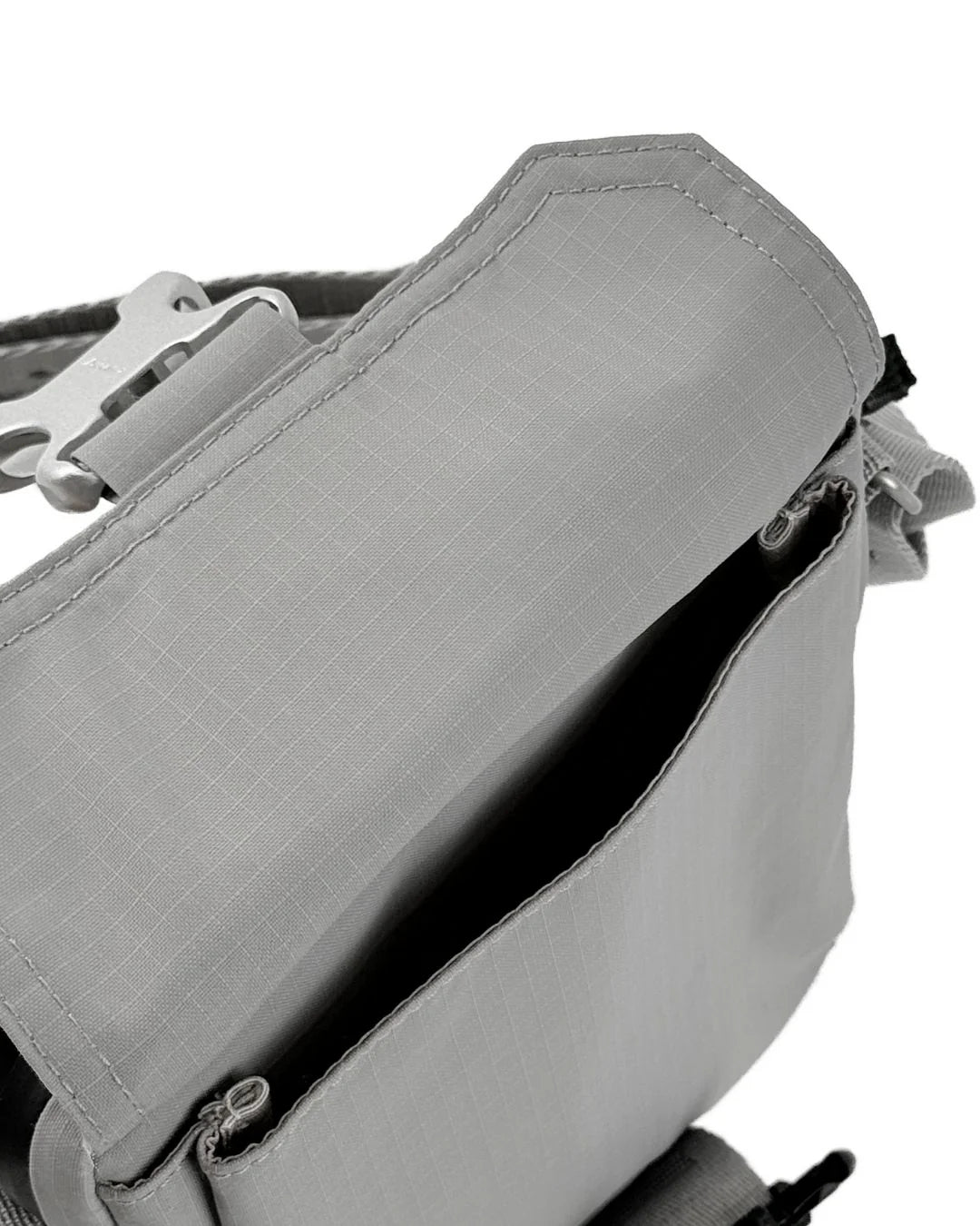 Grey fabric hip bag with a flap top, silver buckle, and zippered pockets.