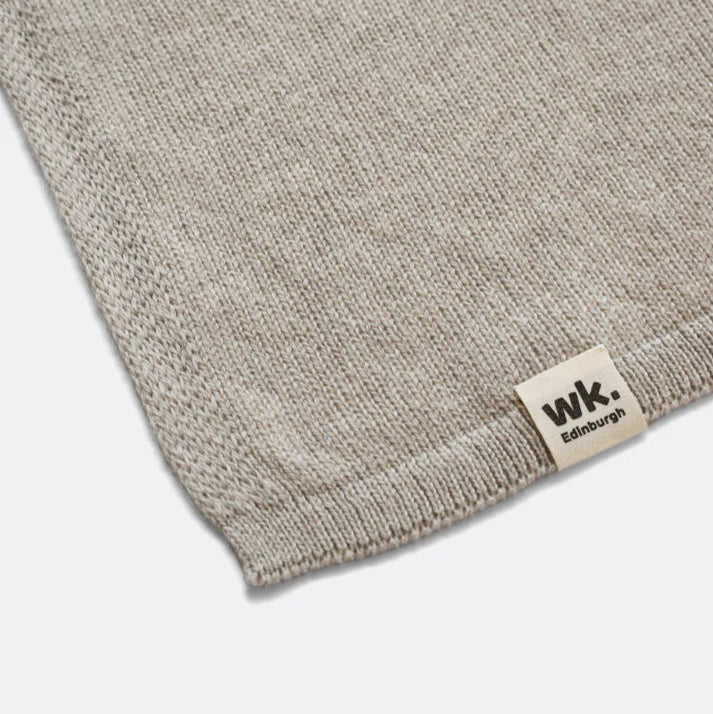 Close-up of a light beige knitted linen fabric swatch with a small "WK. Edinburgh" label.