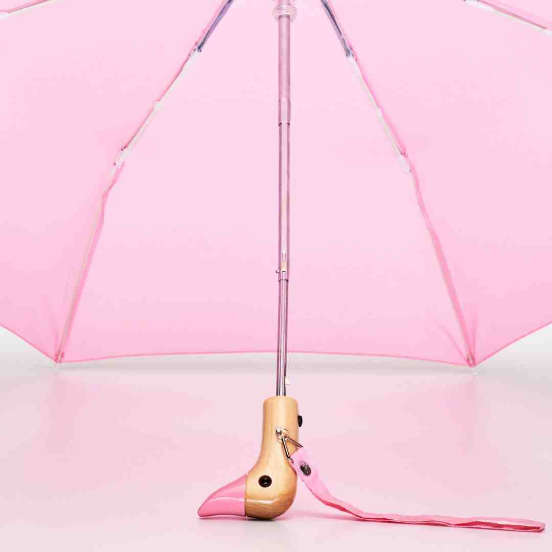 Pink umbrella with a unique flamingo-shaped wooden handle.