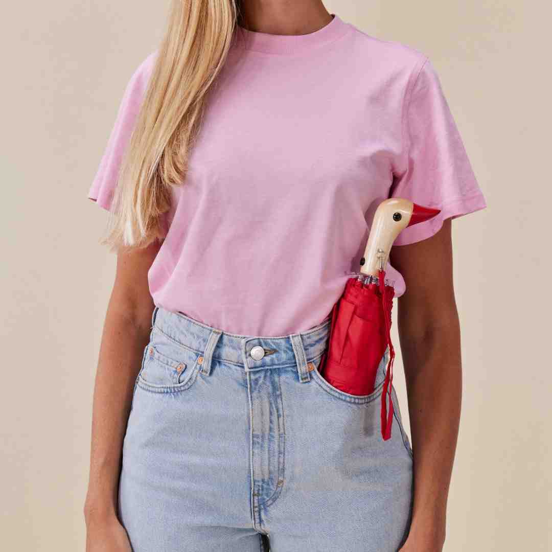 Red compact umbrella with a wooden bird-shaped handle, tucked into a back jeans pocket.