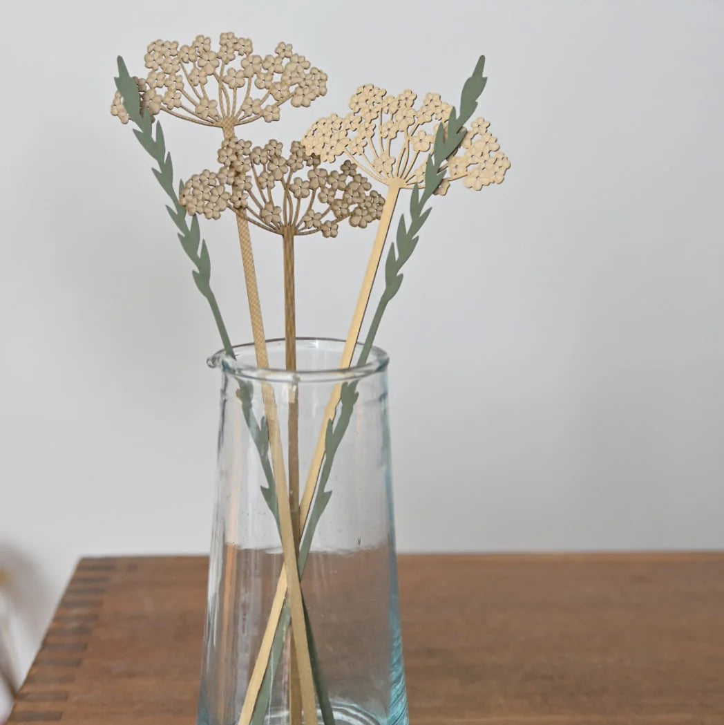Clear glass vase with decorative sticks on a wooden surface, with 'Hannah' visible in the background.