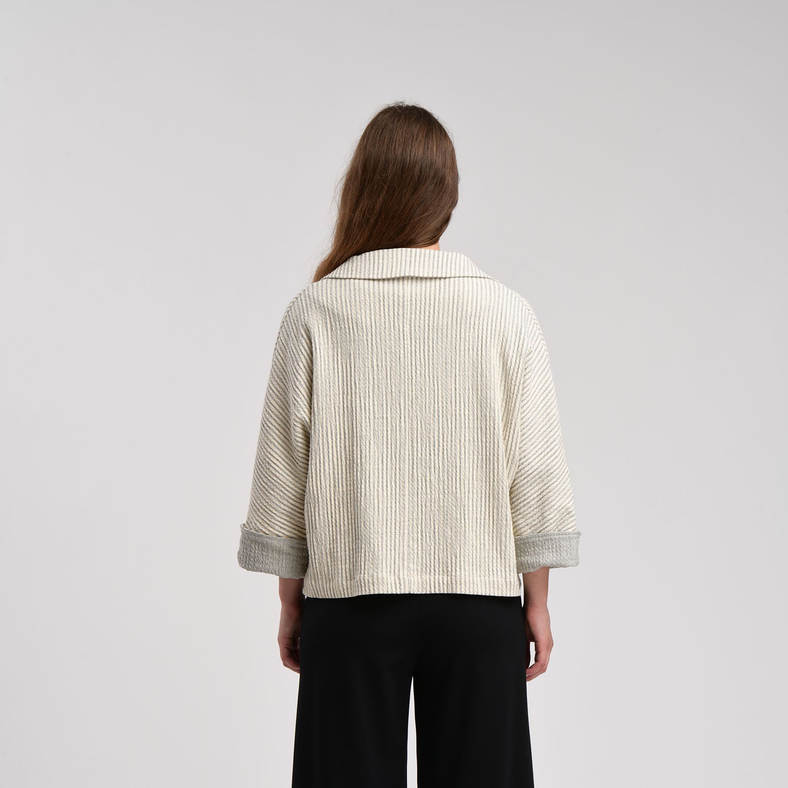 Off-white vertically striped cropped jacket with three-quarter sleeves and grey cuffs, viewed from the back.