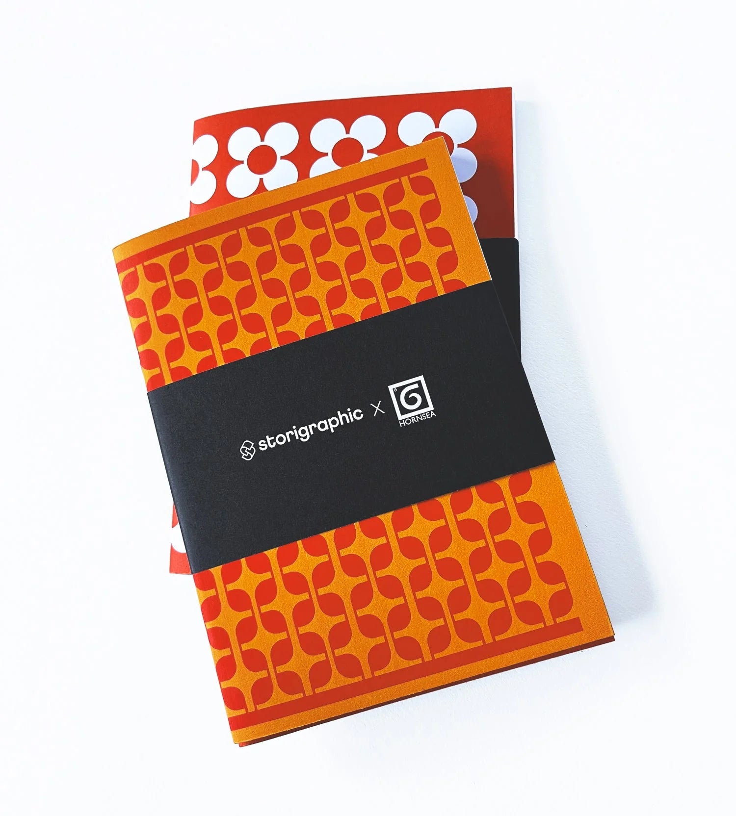 Two notebooks with orange geometric patterns and a black band featuring a logo on a white background