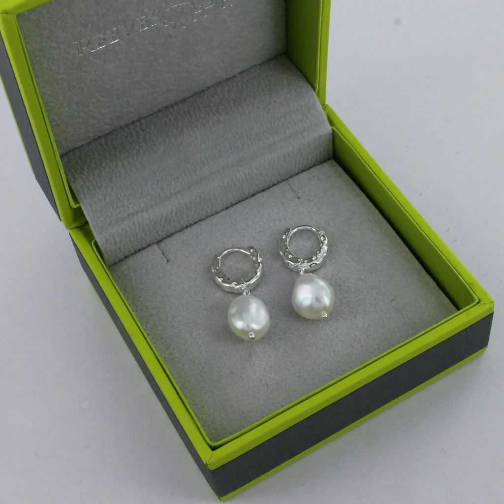 Pair of silver hoop earrings with dangling white pearls.