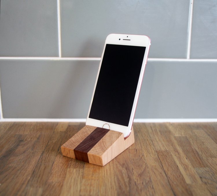 Wooden smartphone stand; light and dark wood, angled design.