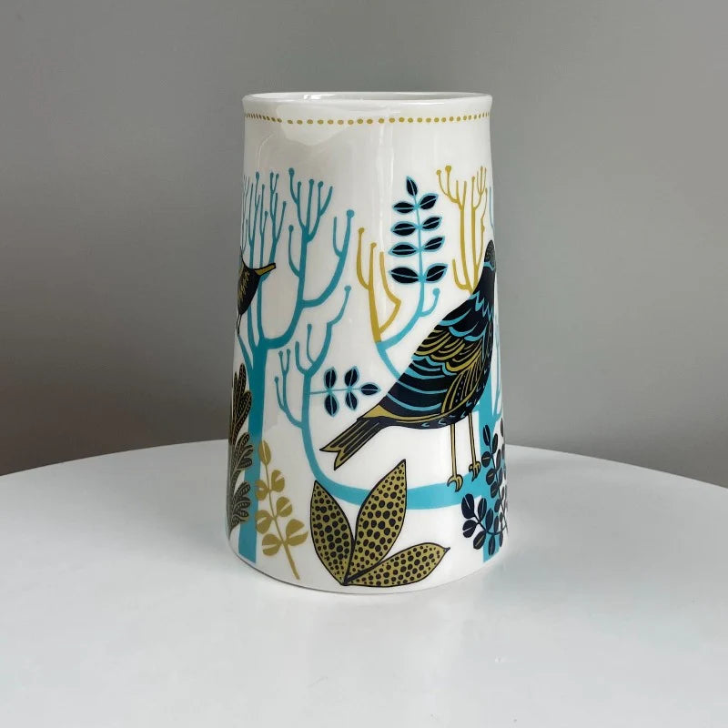 Ceramic vase with bird and plant design on a gray background
