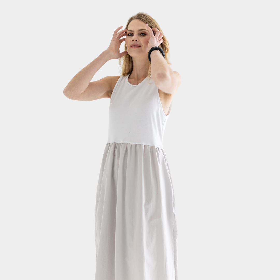 Woman in a sleeveless midi dress; white bodice and light beige skirt.
