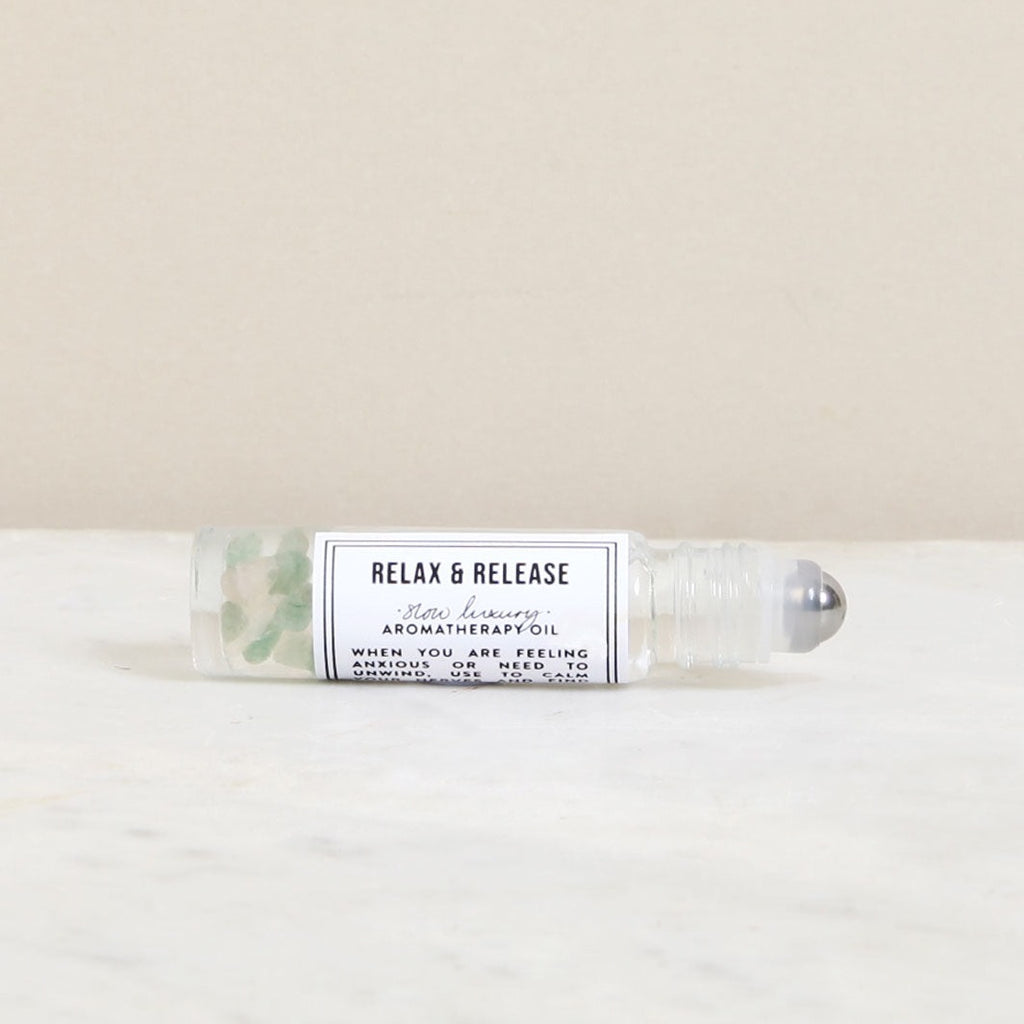 Relax & Release aromatherapy roll-on oil. Clear glass bottle with silver rollerball and small green stones inside.