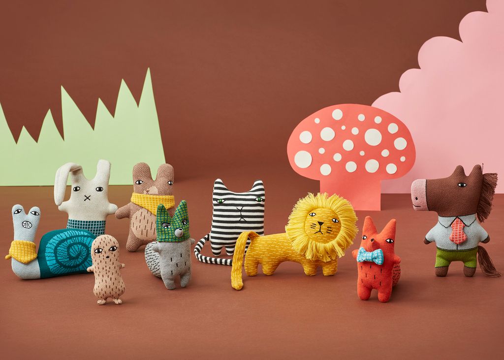 Colorful toy animals on a brown background with a pink mushroom and green mountains.