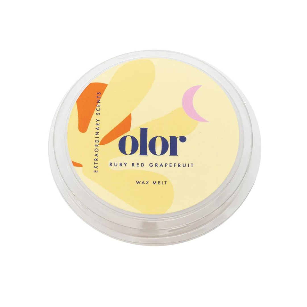 Olor Ruby Red Grapefruit wax melt in a clear plastic container with a yellow label featuring abstract shapes.