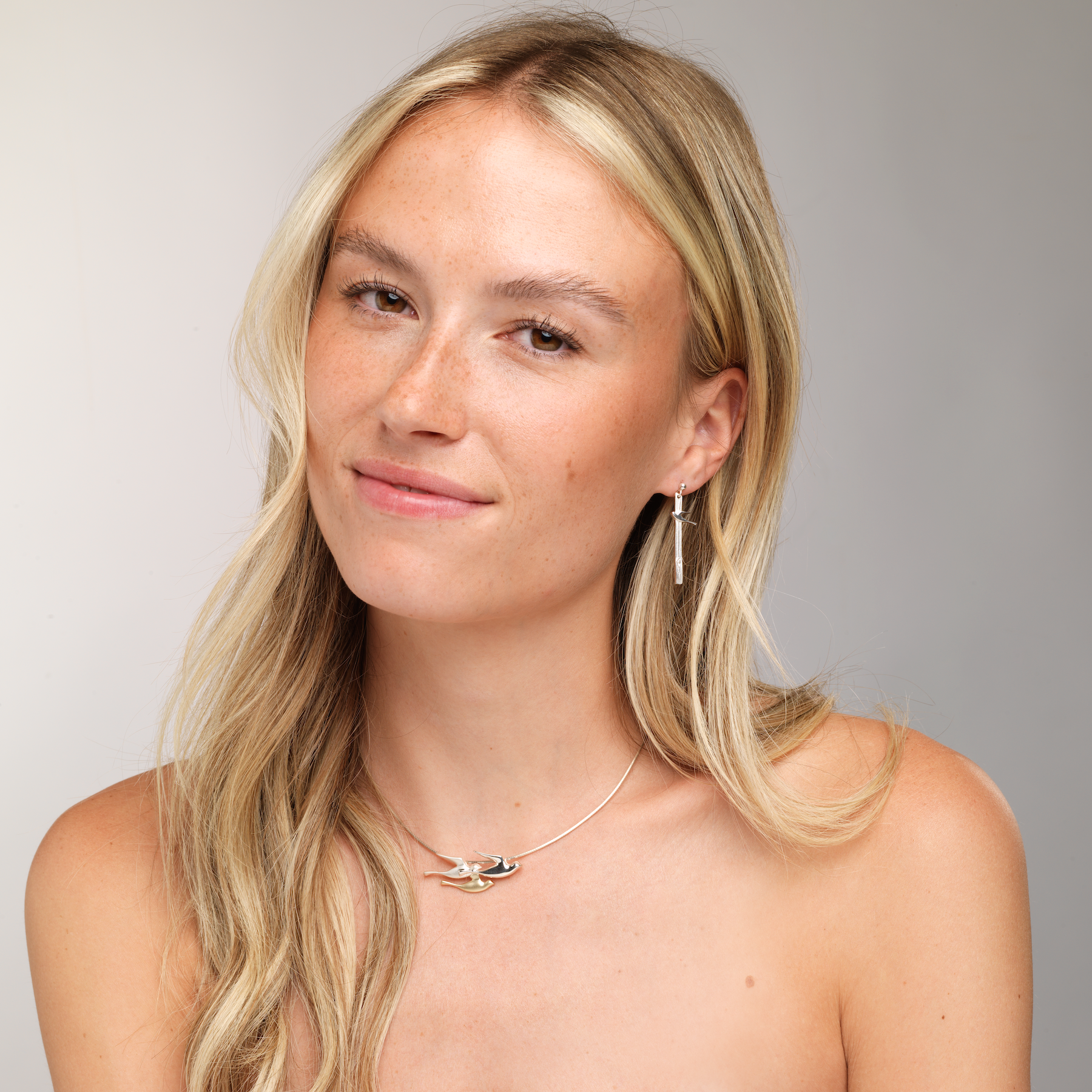 woman looking to camera with birdland necklace and drop earring