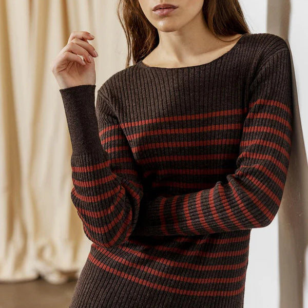 Woman wearing a black and red striped sweater against a neutral background