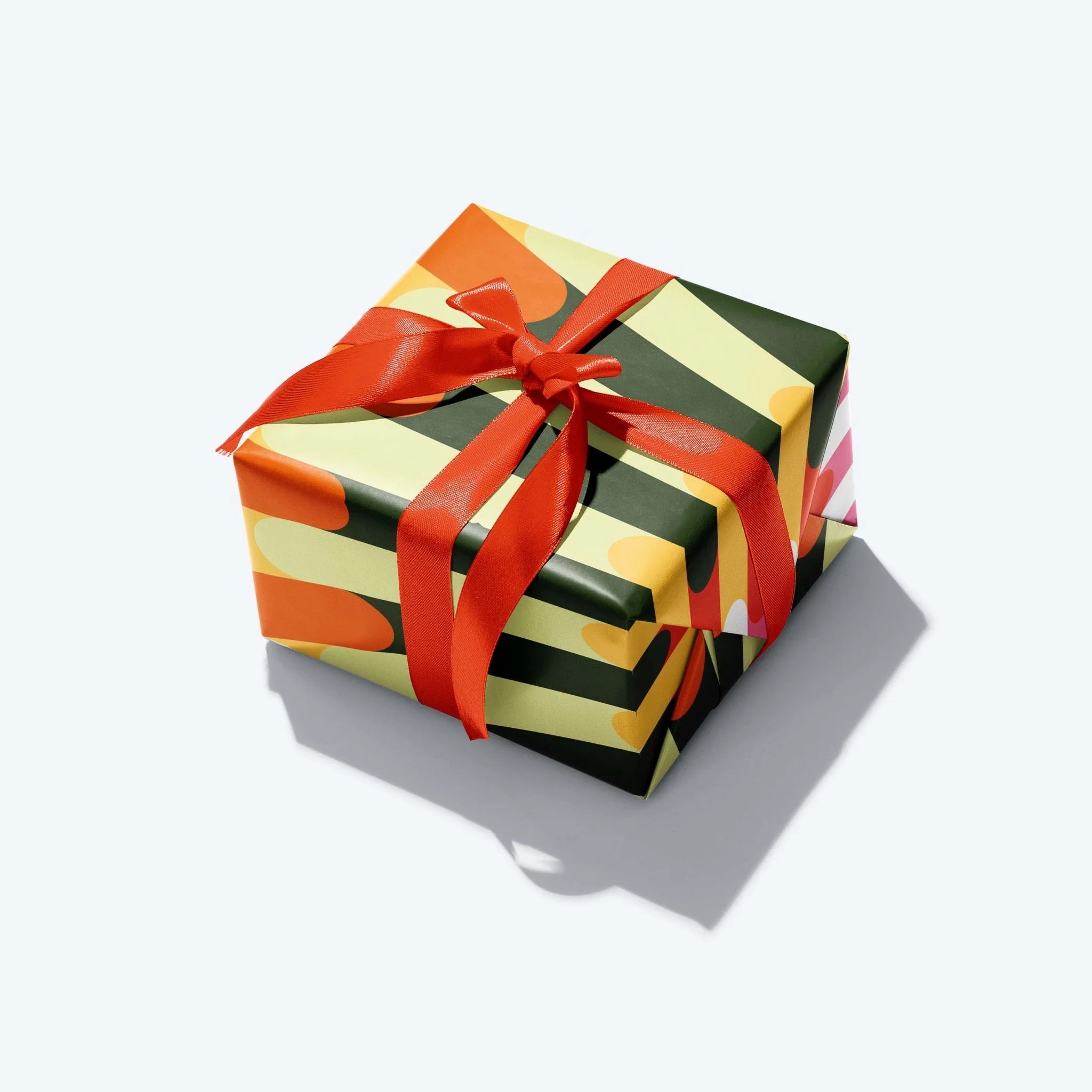 Gift box with colorful striped wrapping and a red ribbon on a white background