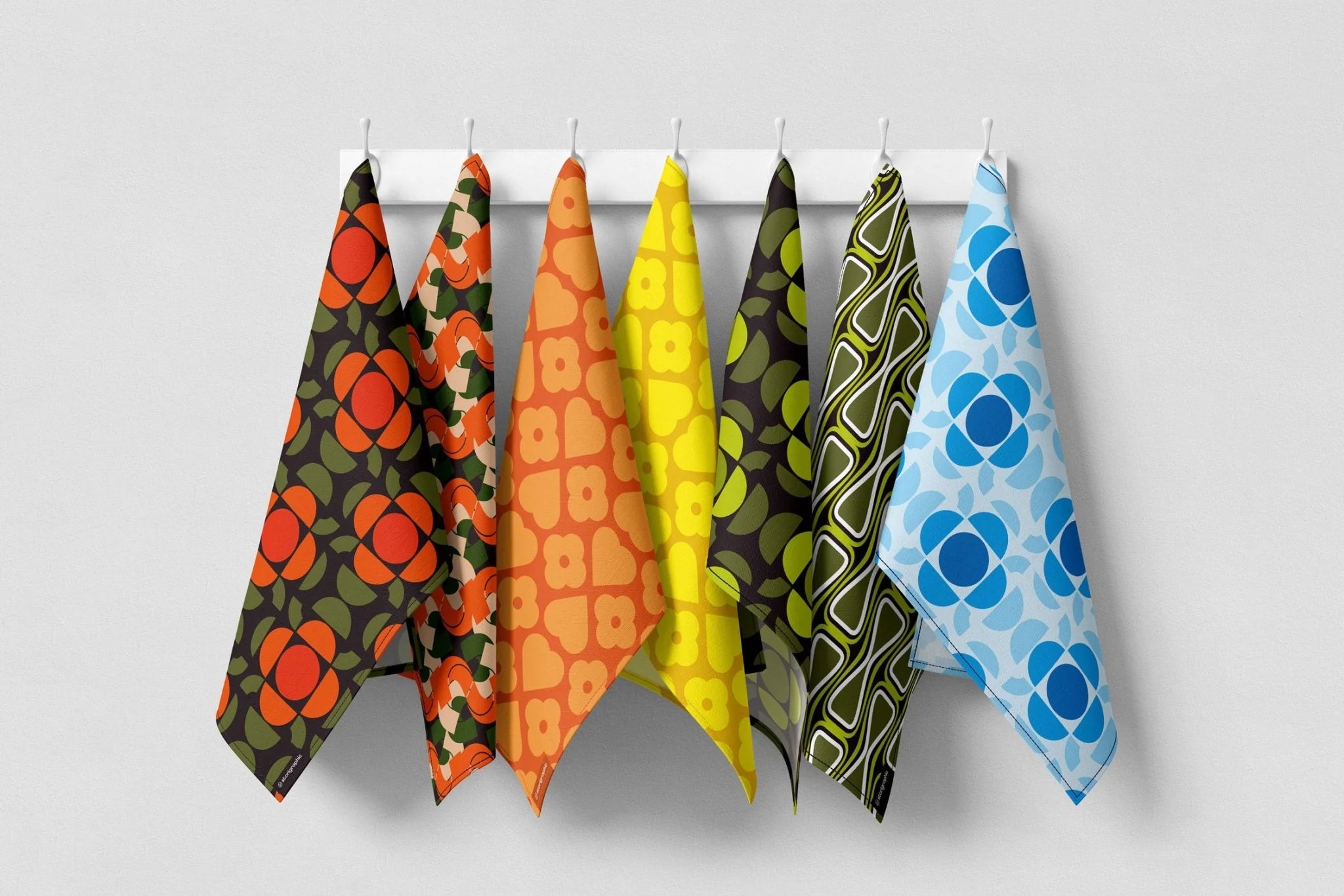 Set of colorful patterned towels hanging on a rack against a white background