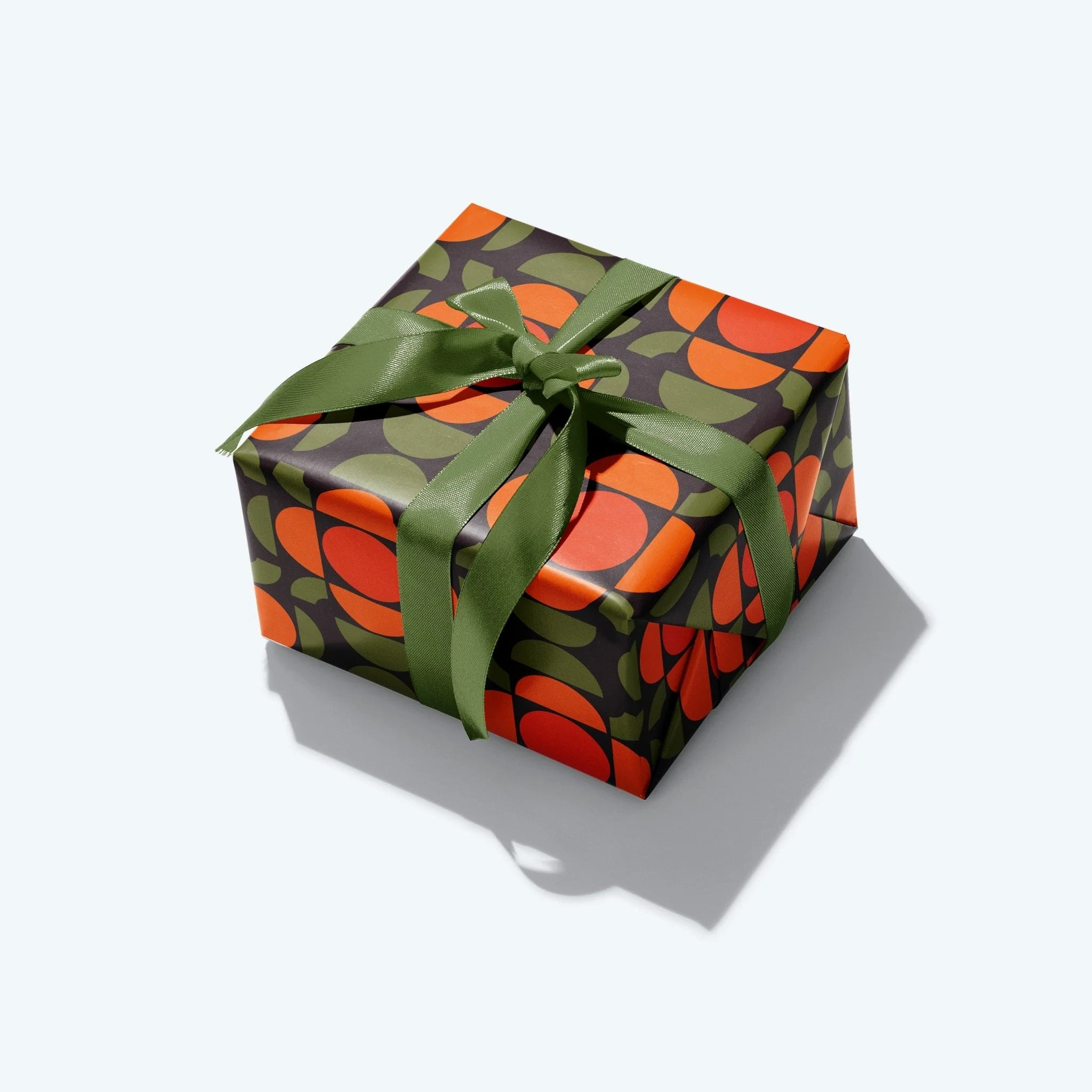 Gift box with green and orange patterned paper and a green ribbon on a white background
