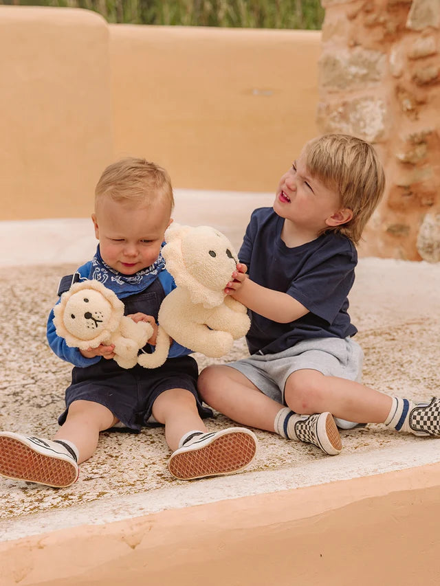 Two cream-colored lion plush toys; one larger than the other.  The smaller lion is being held by a toddler.