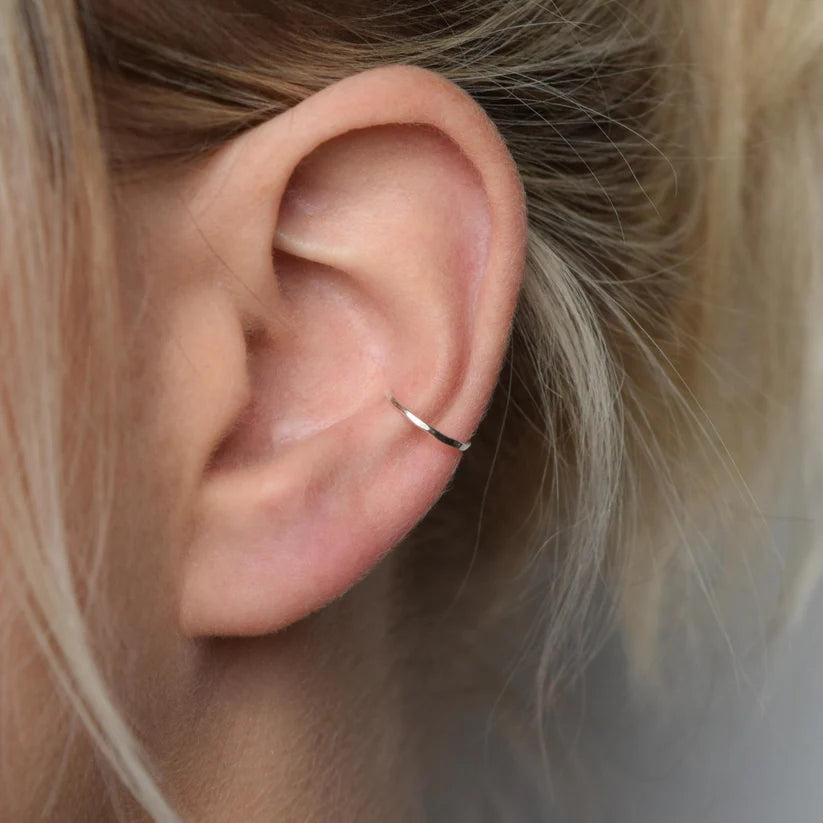 Silver hammered ear cuff on a person's ear.