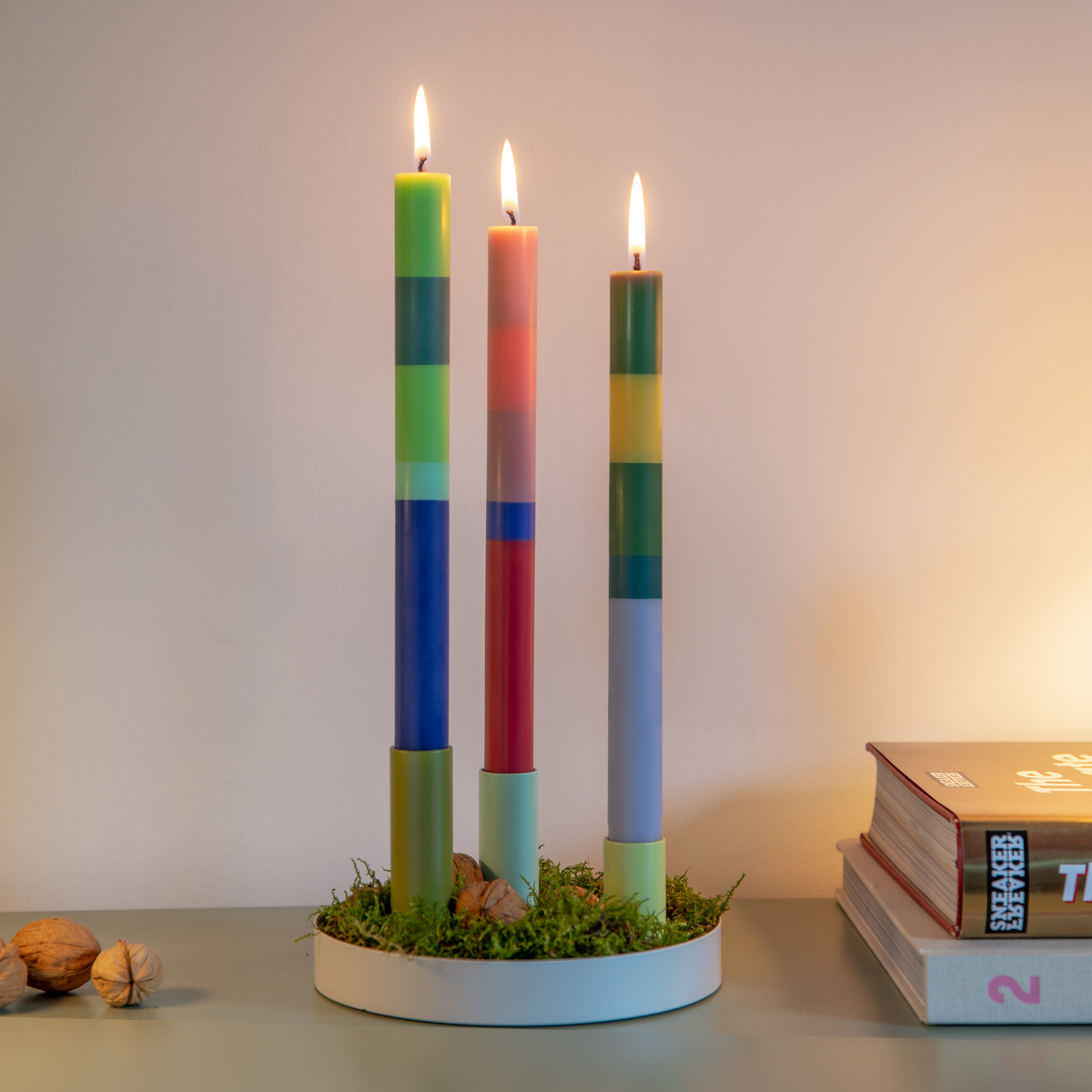 Three colorful candles in a holder with a blurred background