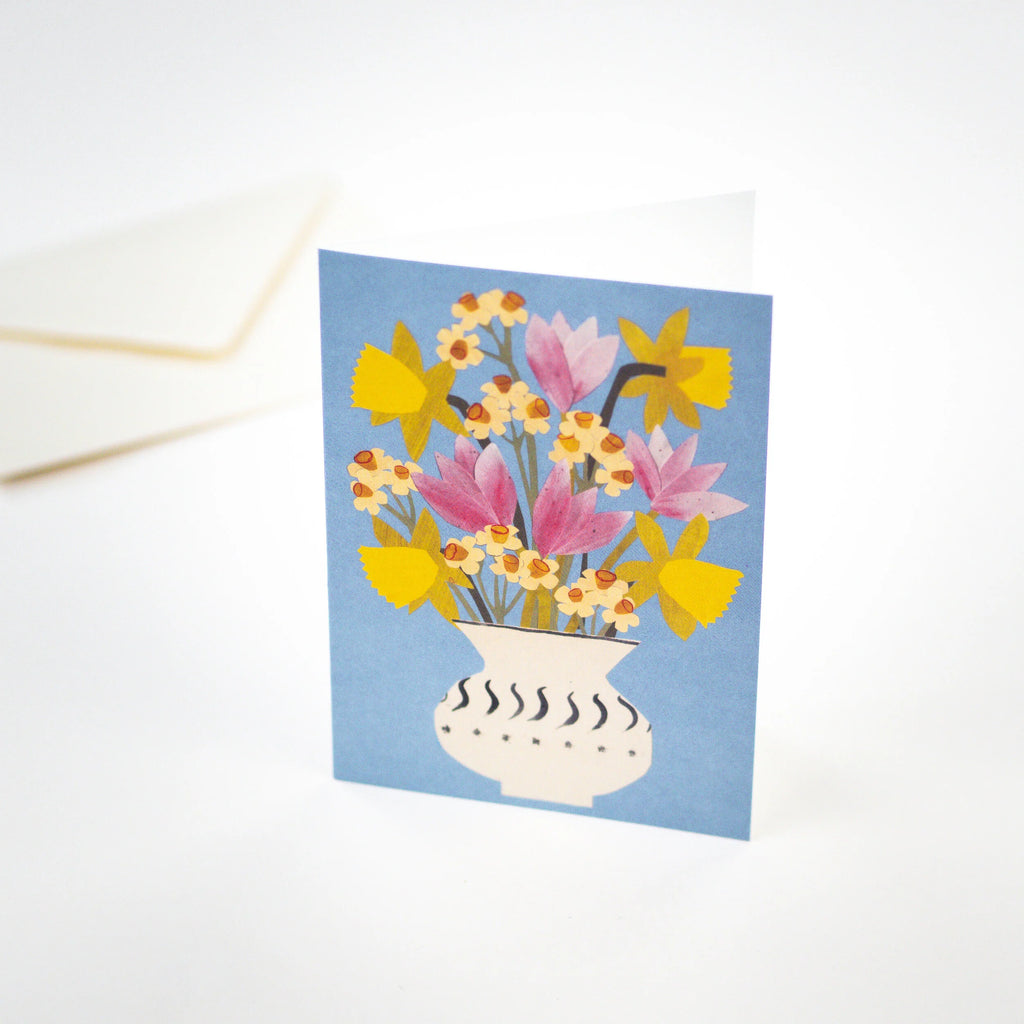 Greeting card depicting a stylized floral arrangement of daffodils and tulips in a white vase with black detailing, on a