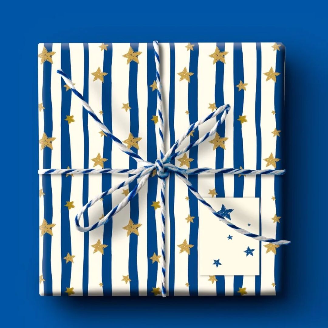 Gift wrapped in blue and white striped paper with gold stars, tied with twine, and a small blank tag.