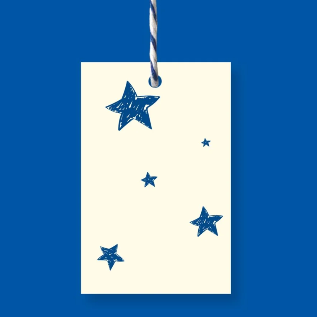 Off-white gift tag with blue hand-drawn stars, hanging from twine.