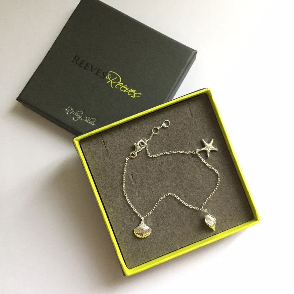 Sterling silver bracelet featuring a starfish and two shell charms.