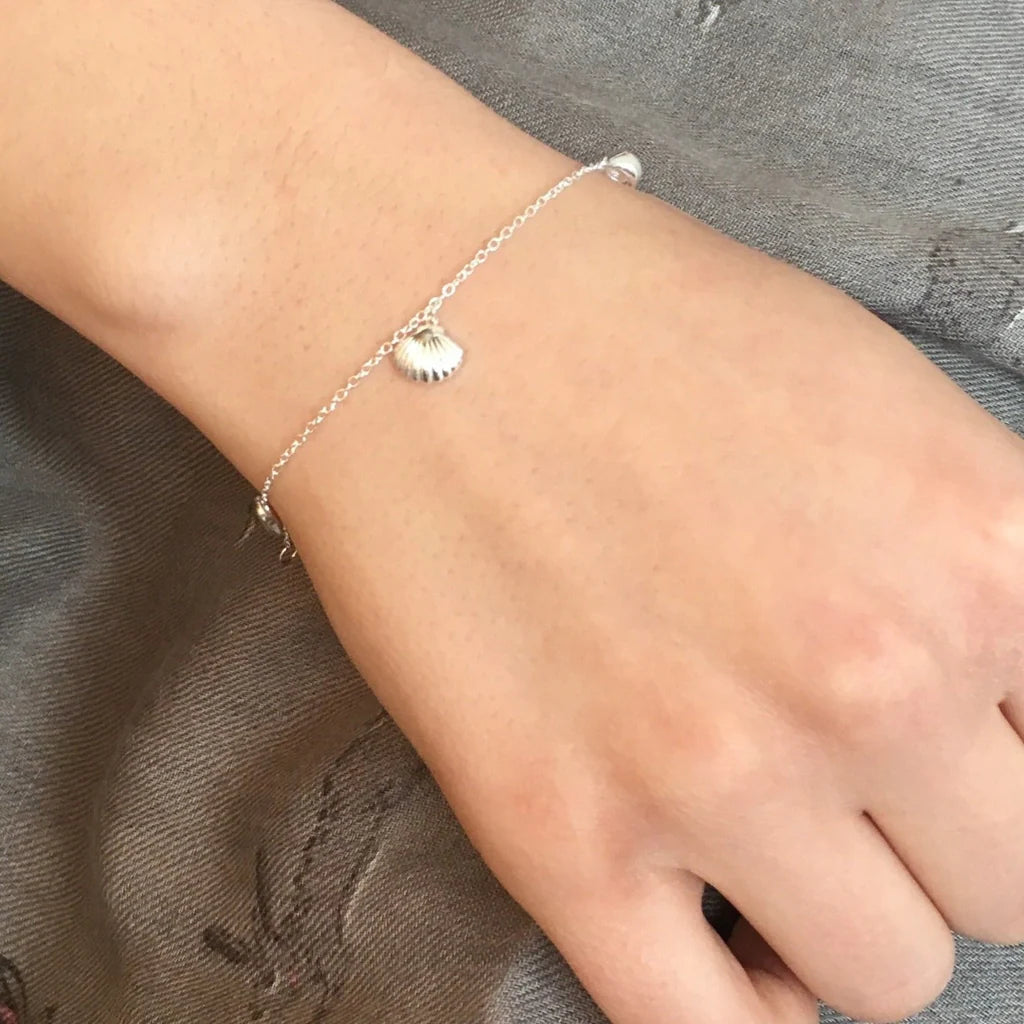 Silver chain bracelet with small shell charm.