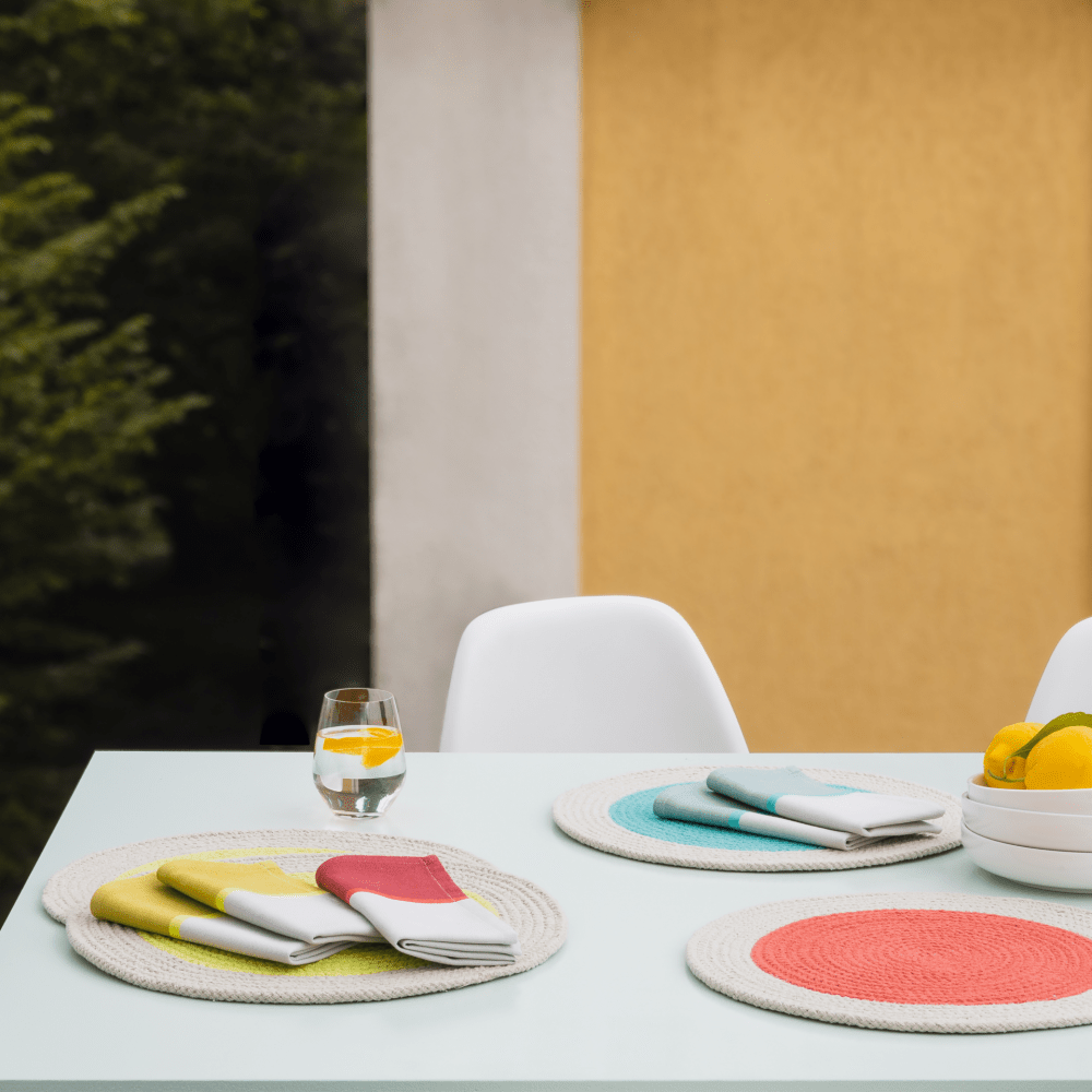 Set of colorful, folded napkins on round, rope placemats.