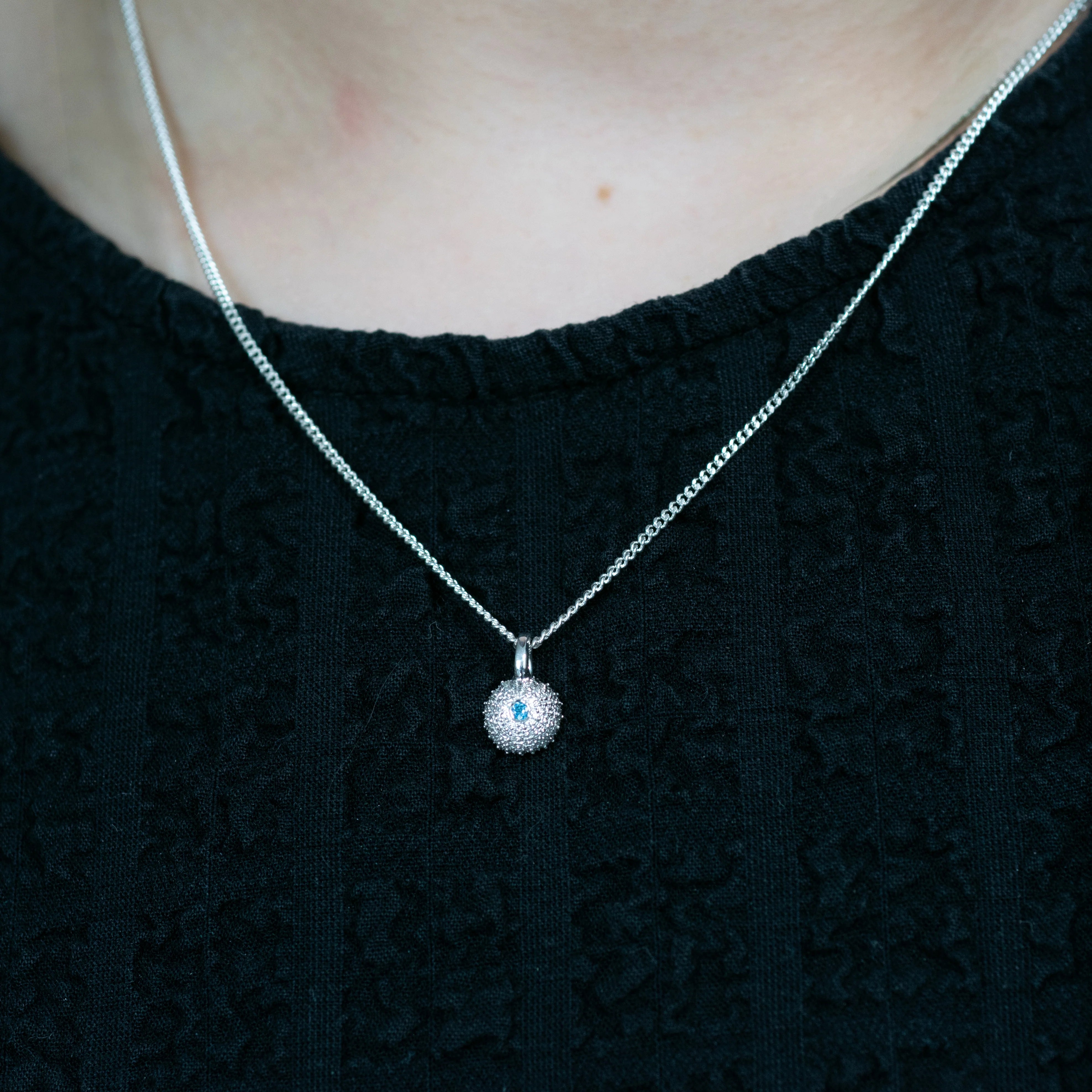 Silver necklace with a pendant on a black top