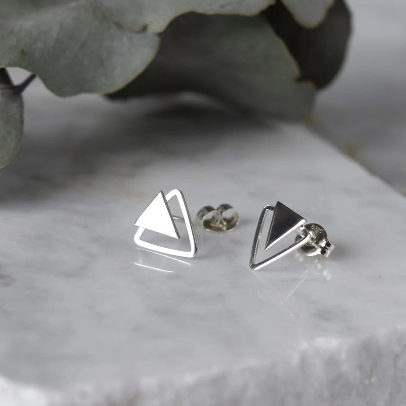 Pair of silver triangle stud earrings; one triangle is solid, the other is an outline.