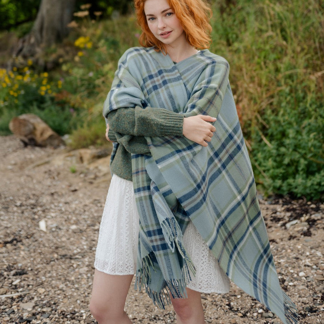 Woman with red hair wearing a green plaid shawl in a natural setting
