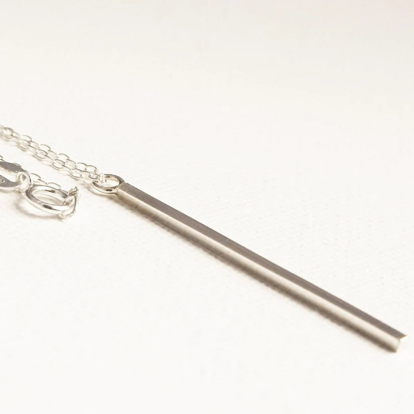 Silver bar necklace with delicate chain.  Long, slender bar pendant hangs from a simple chain.