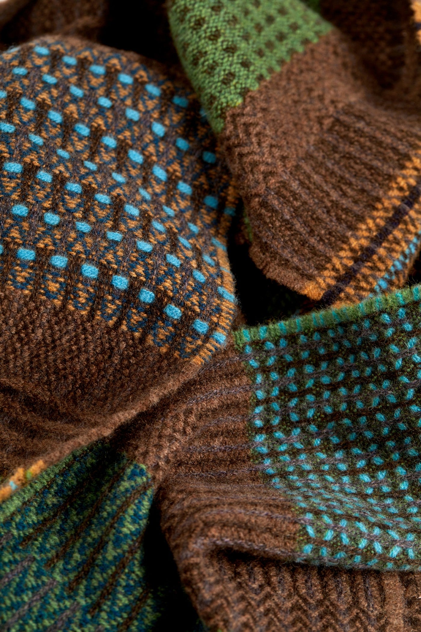 Close-up of brown and green knitted fabric with textured patterns