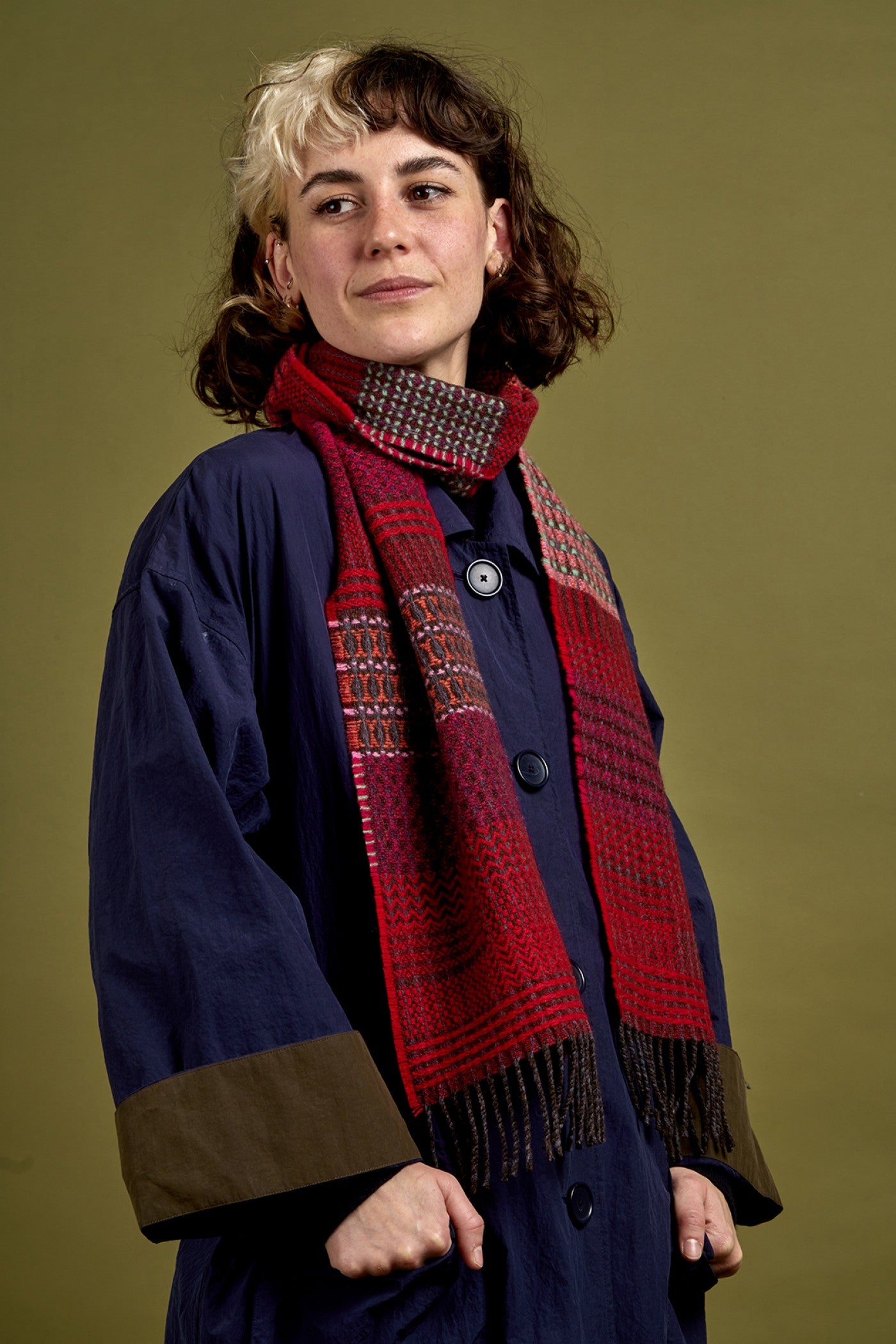 Woman wearing a red scarf and dark coat against a green background