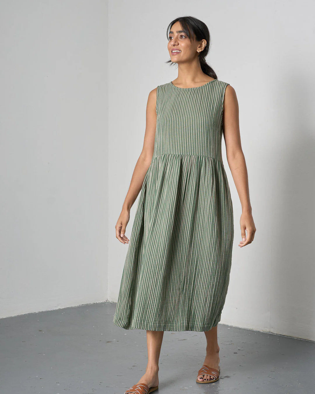 Woman wearing a green striped dress against a plain background