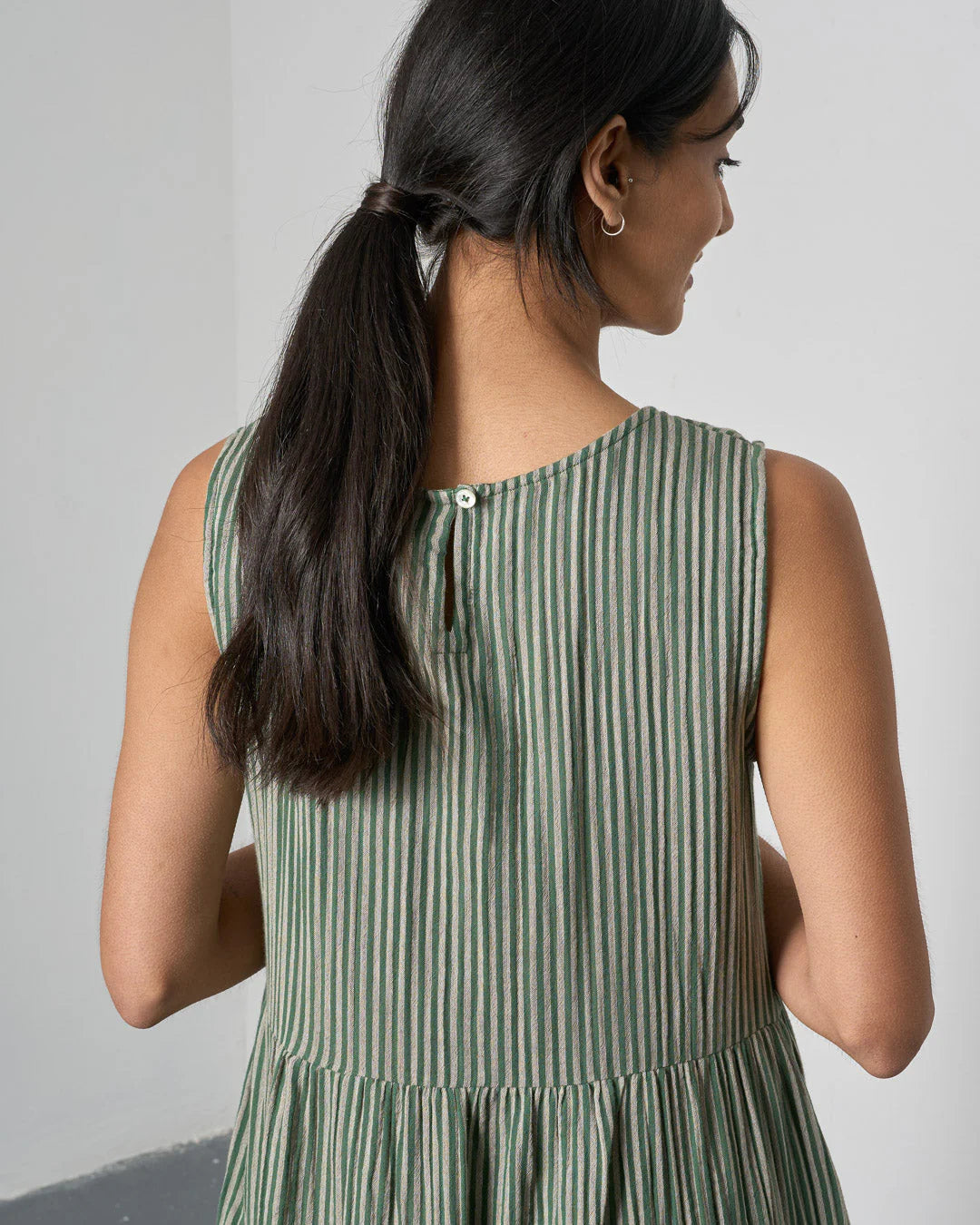 Woman wearing a green and white striped dress against a plain background