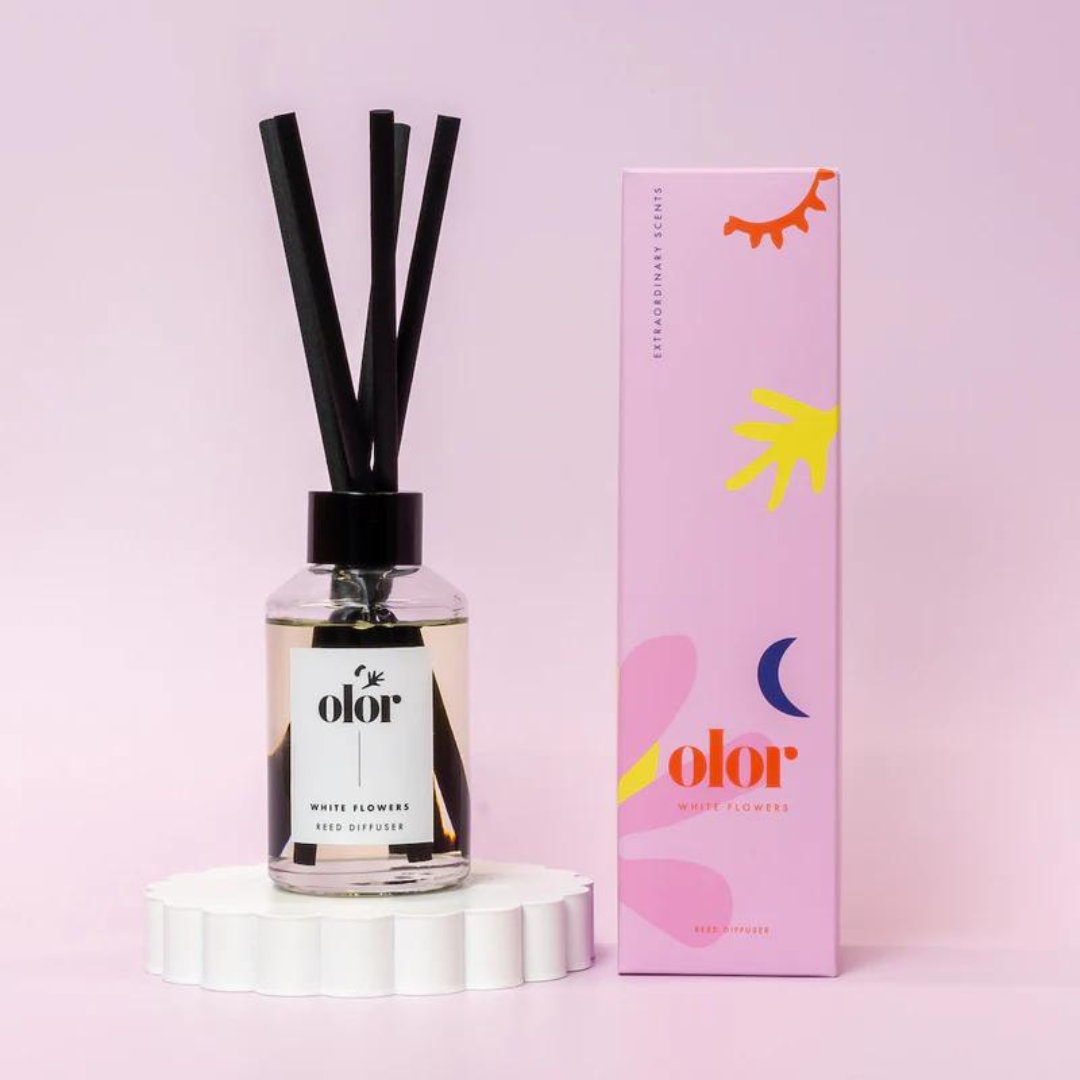 Olor White Flowers reed diffuser in a clear glass bottle with black reeds and a minimalist label.