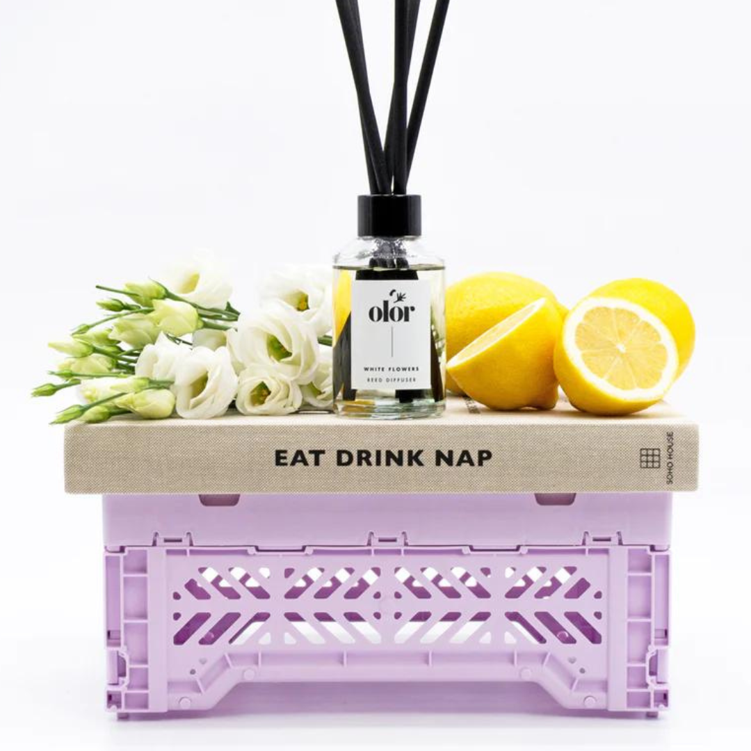 Olor White Flowers reed diffuser in a clear glass bottle with black reeds.