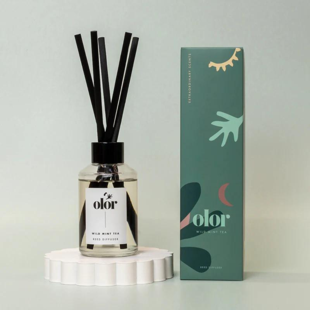 Olor Wild Mint Tea reed diffuser in clear glass bottle with black reeds and matching box.