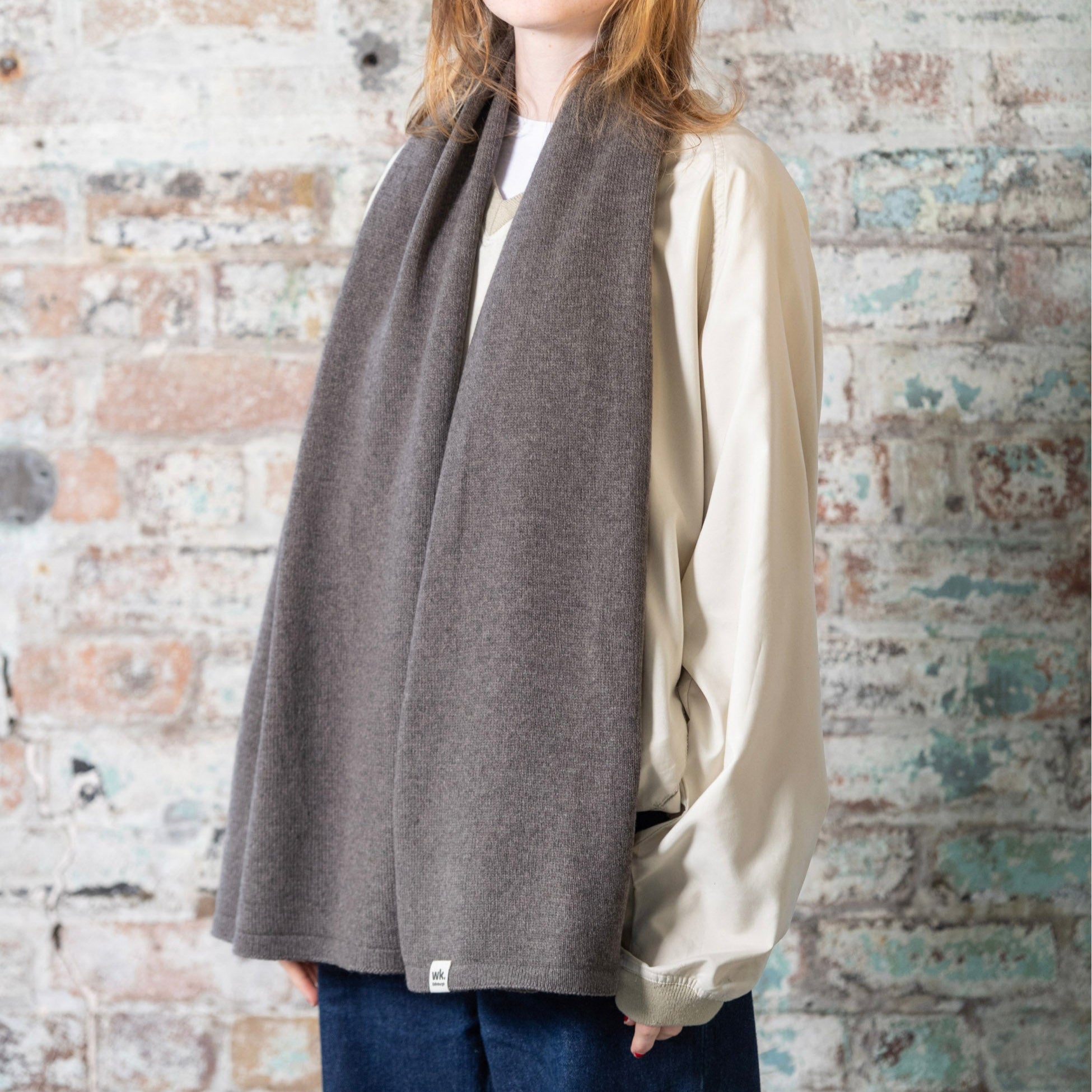 A dark gray, ribbed knit scarf.  The scarf is loosely draped around a person's neck.