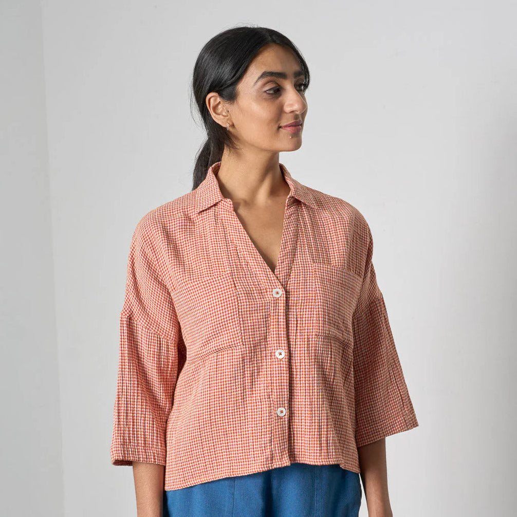 Woman wearing a red checkered shirt and blue pants against a white background