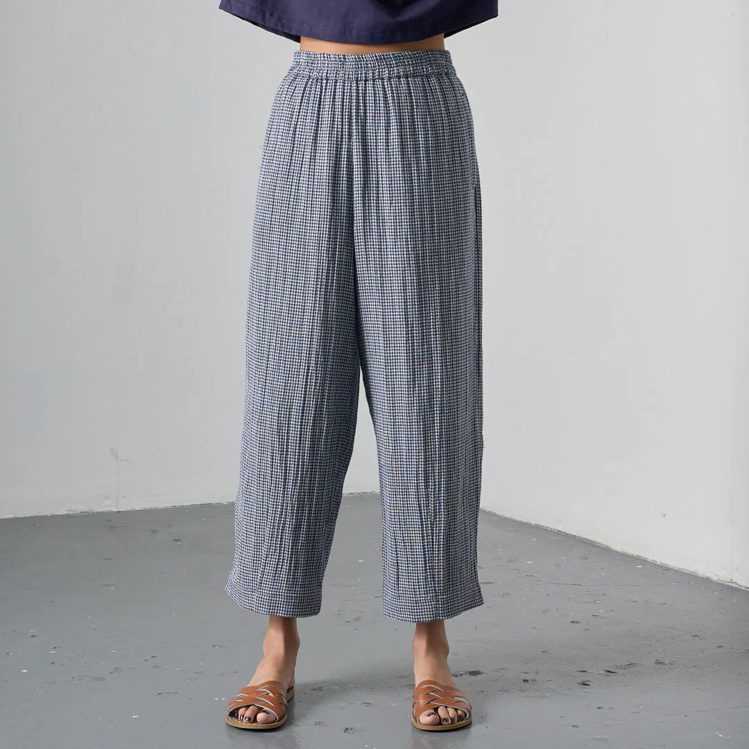 Person wearing blue checkered pants and a navy top against a plain background