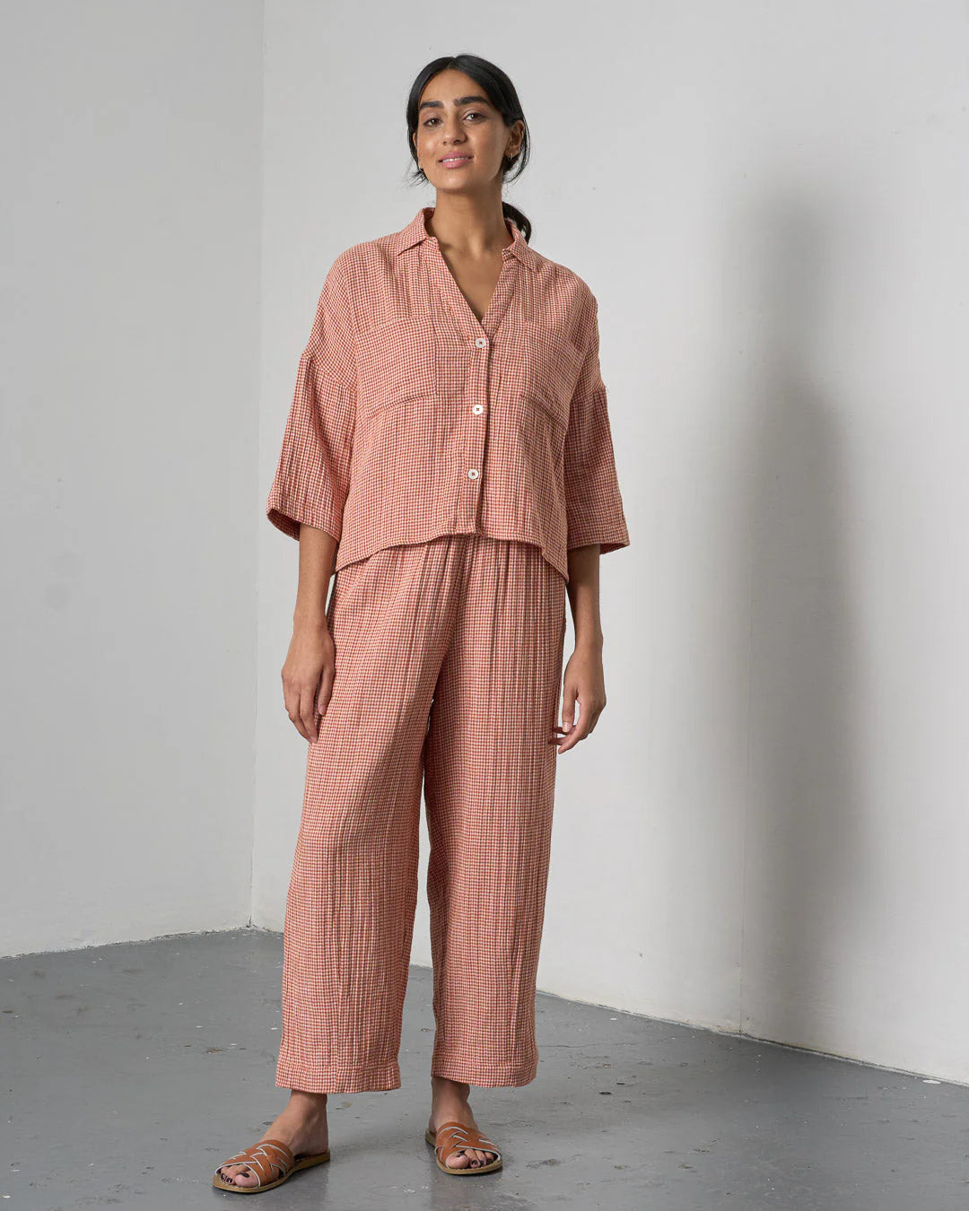 Woman wearing a matching pink outfit with a shirt and pants against a plain background