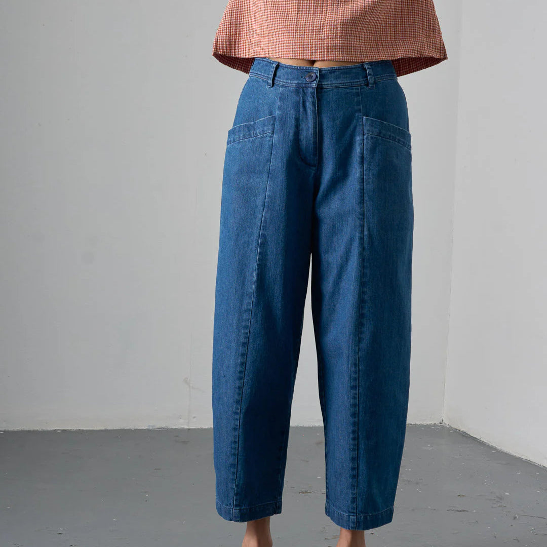 Person wearing blue pants and a red checkered top against a gray background