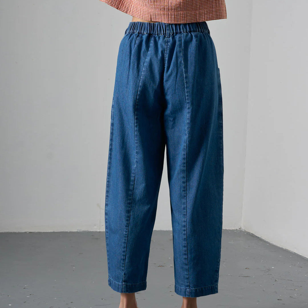 Person wearing blue pants and a brown top against a gray background