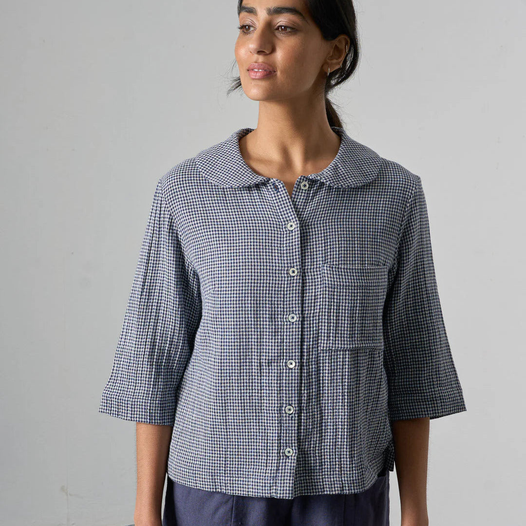 Woman wearing a checkered shirt with short sleeves against a plain background